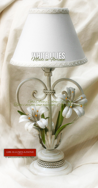 Bedside table lamp in wrought iron with white lilies and an antique white enamel finish. A handmade Italian lampshade with matching colour trimmings.